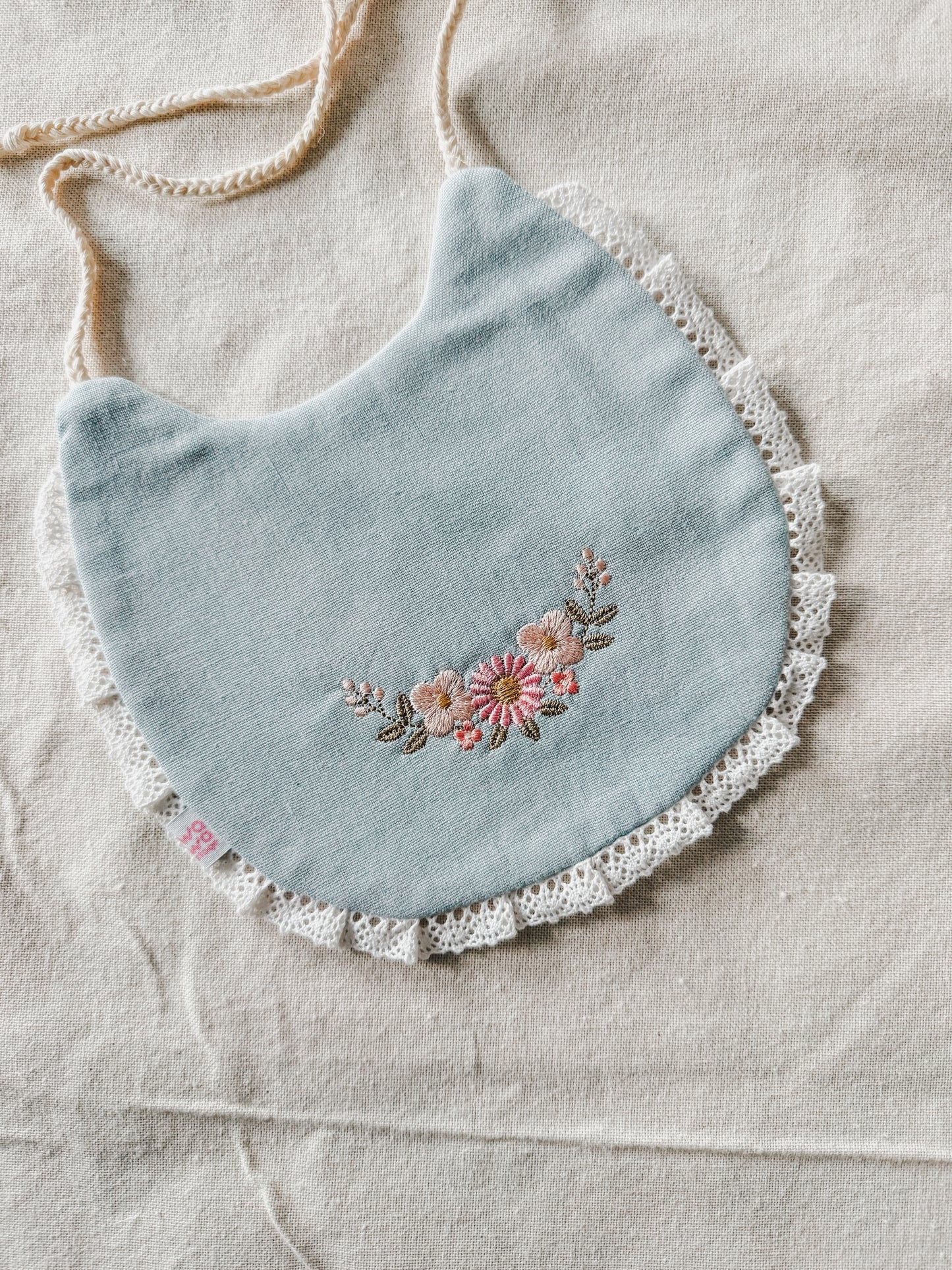Babero bordado semia aro de flores delicadas celeste