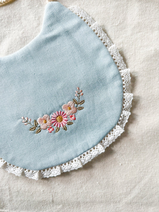 Babero bordado semia aro de flores delicadas celeste